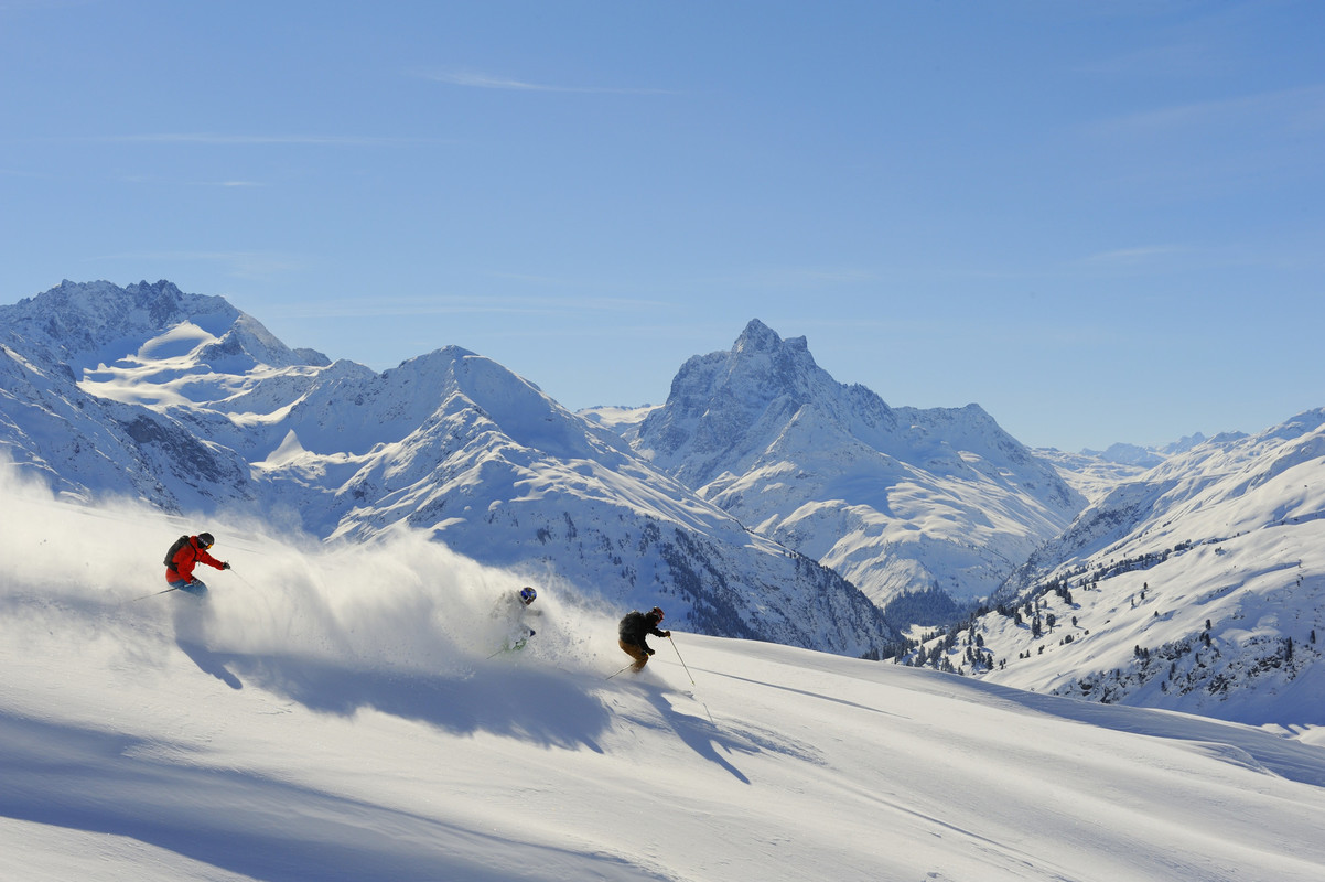 Skiers moving through fresh powder in the Alps
